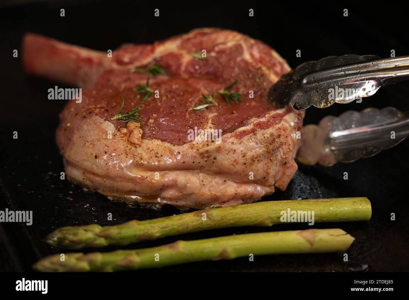 Cucinare una bistecca di costata su un grill, un grill o un barbecue. Una costoletta con osso che sfrigolerà un barbecue con fiamma o fiamme. Concetto di carne di manzo Foto Stock