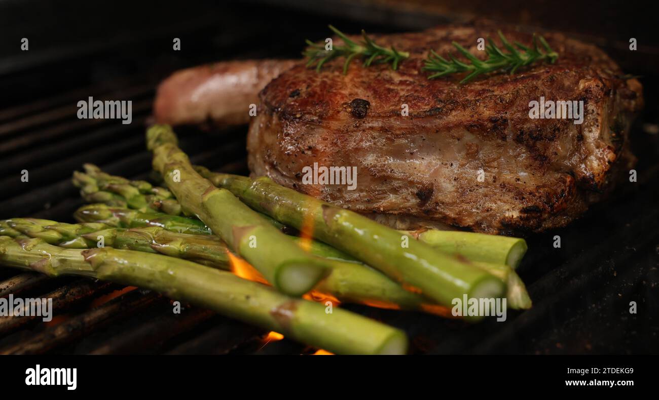 Cucinare una bistecca di costata su un grill, un grill o un barbecue. Una costoletta con osso che sfrigolerà un barbecue con fiamma o fiamme. Concetto di carne di manzo Foto Stock
