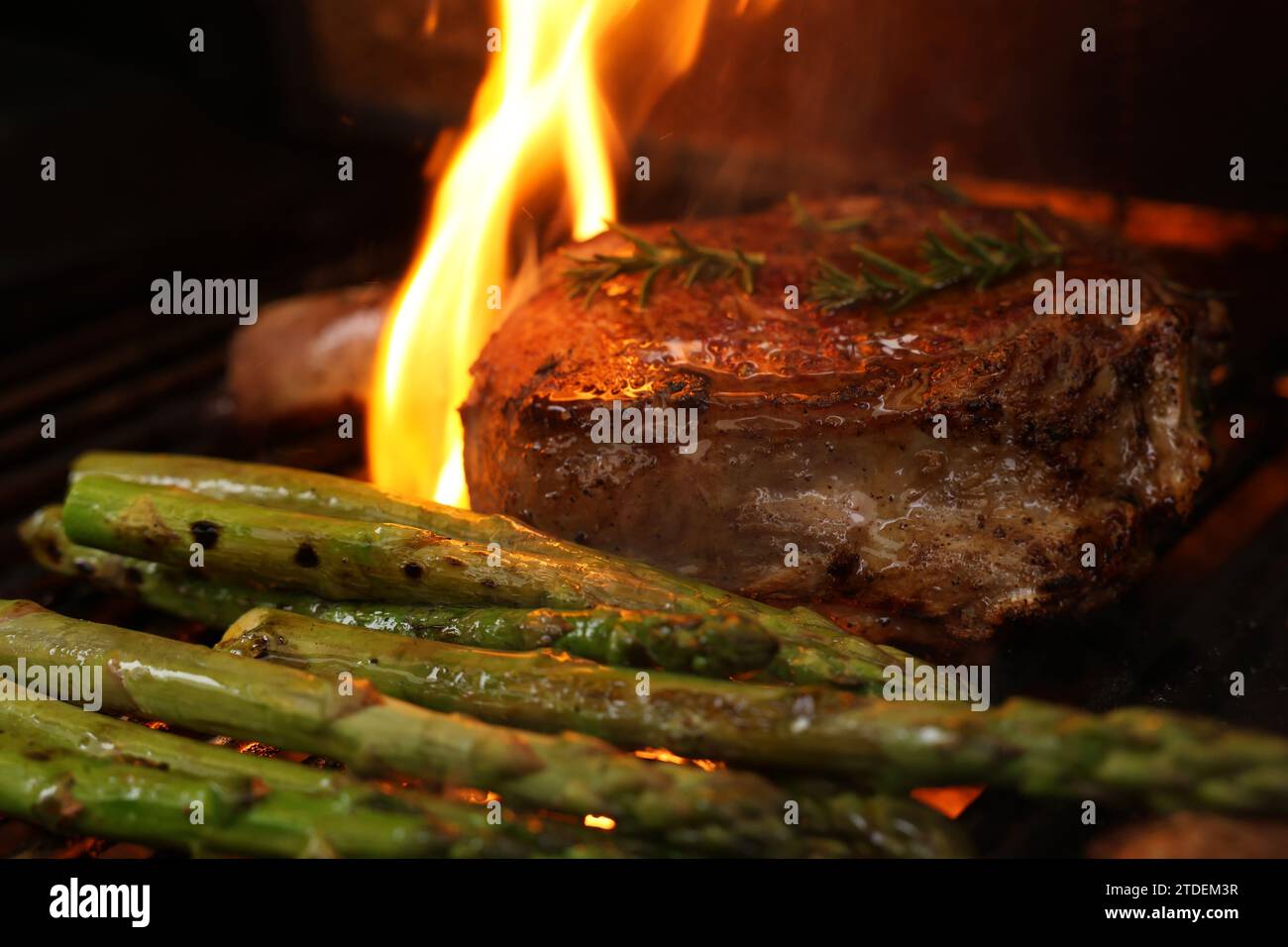 Cucinare una bistecca di costata su un grill, un grill o un barbecue. Una costoletta con osso che sfrigolerà un barbecue con fiamma o fiamme. Concetto di carne di manzo Foto Stock