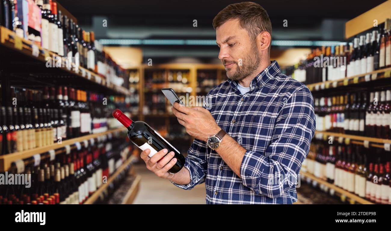 Il cliente uomo sceglie il vino in un negozio di liquori utilizzando il suo smartphone per la scansione del codice QR. Servizio clienti ed esperienza. Foto Stock