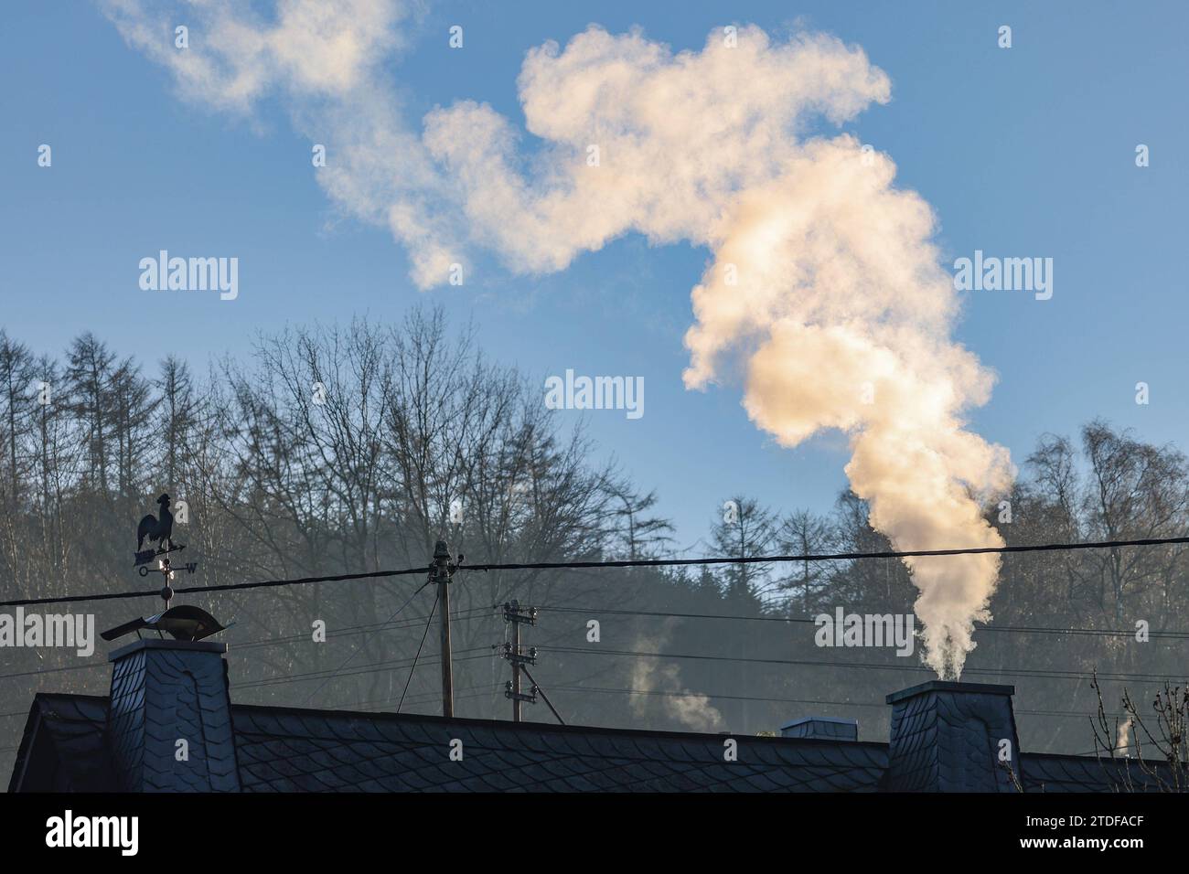 Ein Qualmender, Dampfender Schornstein auf einem Haus a Siegen. Symbolbild, Energiekosten, Energiepolitik AM 18.12.2023 a Siegen/Deutschland. *** Un camino fumante e fumante su una casa a Siegen immagine simbolica, costi energetici, politica energetica al 18 12 2023 a Siegen in Germania Foto Stock