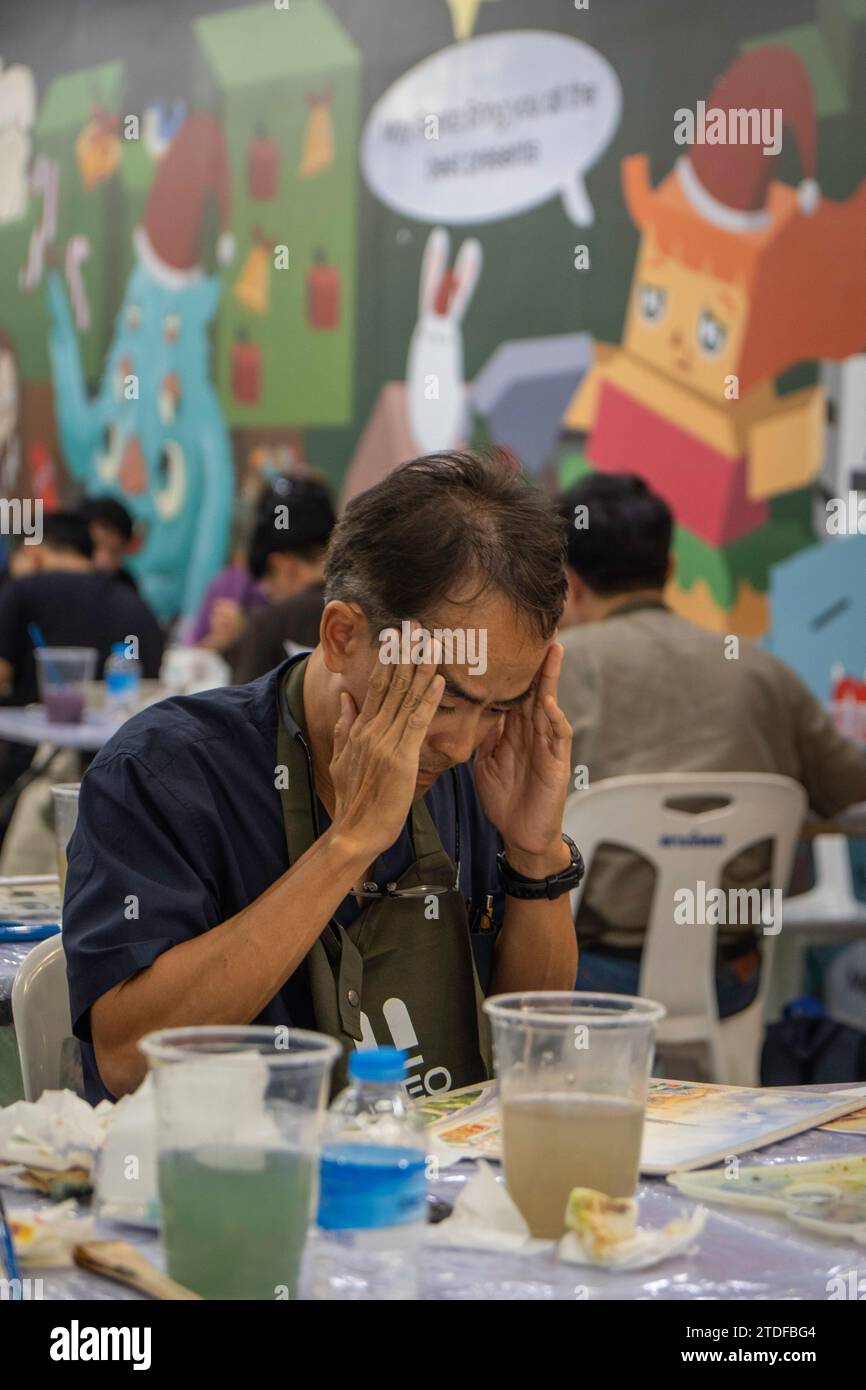 Bangkok, Thailandia. 8 dicembre 2023. Un uomo è visto tenere la testa in mano durante il concorso di pittura ad acquerello "BEM Art Contest", alla stazione MRT Phahon Yothin. La “Metro Art” presso l’MRT Phahon Yothin, sviluppata da Bangkok Expressway and Metro Public (BEM), Bangkok Metro Networks Limited (BMN), e supportato dall'Autorità del Turismo della Thailandia (TAT) è la nuova destinazione Art Space and Art nel cuore della città, poiché la stazione MRT Phahon Yothin collega tutte le aree di Bangkok, dove i visitatori possono imparare le arti in vari campi, fare shopping e vendere opere d'arte. Credito: SOPA Images Limited/Alamy Live News Foto Stock