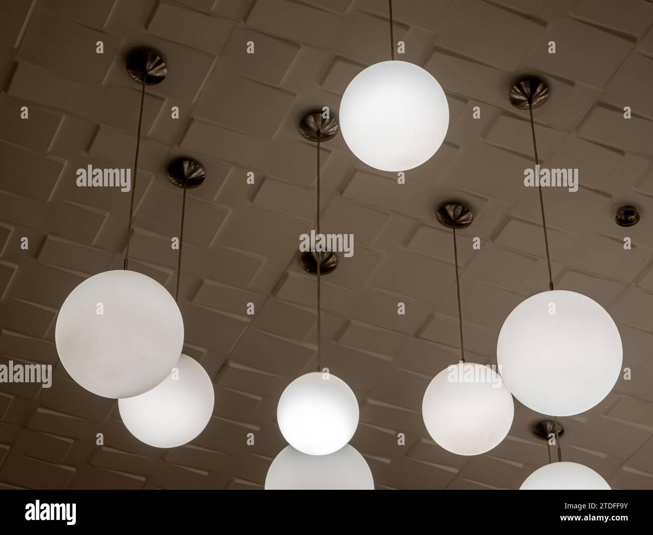 Lampada rotonda, sospesa alternativamente alta e bassa, che decora il soffitto Foto Stock