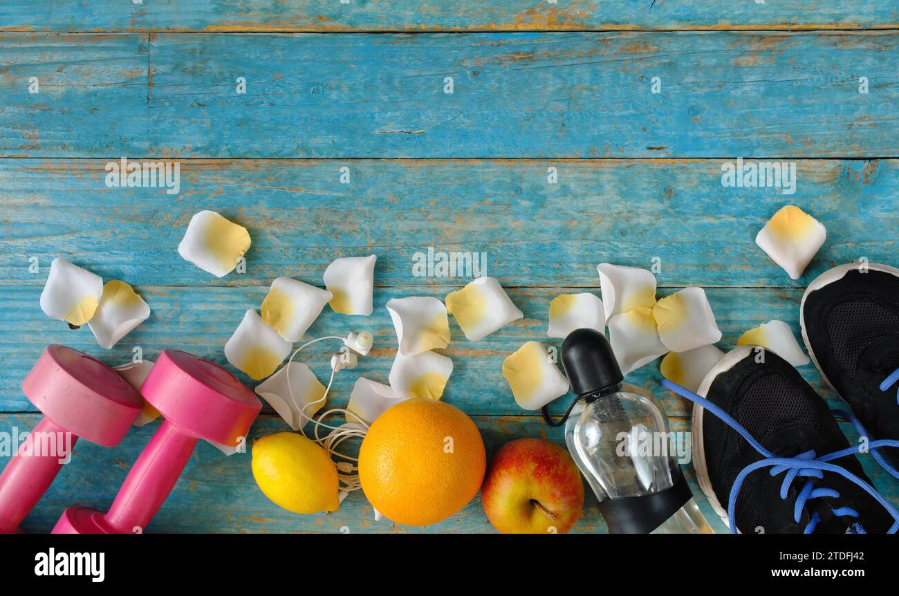 sport e fitness in primavera ed estate, piatto con attrezzature sportive, petali, acqua e frutta. Spazio fotocopie gratuito, tecnica di spazio negativo Foto Stock