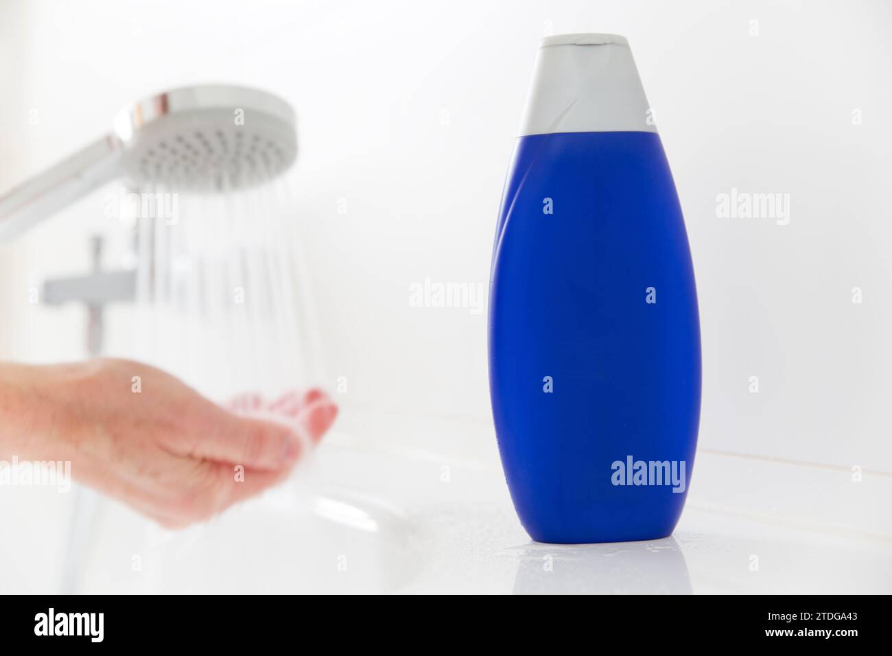 Shampoo in piedi su una vasca da bagno con le mani e acqua fluente sullo sfondo - spazio copia sulla bottiglia Foto Stock
