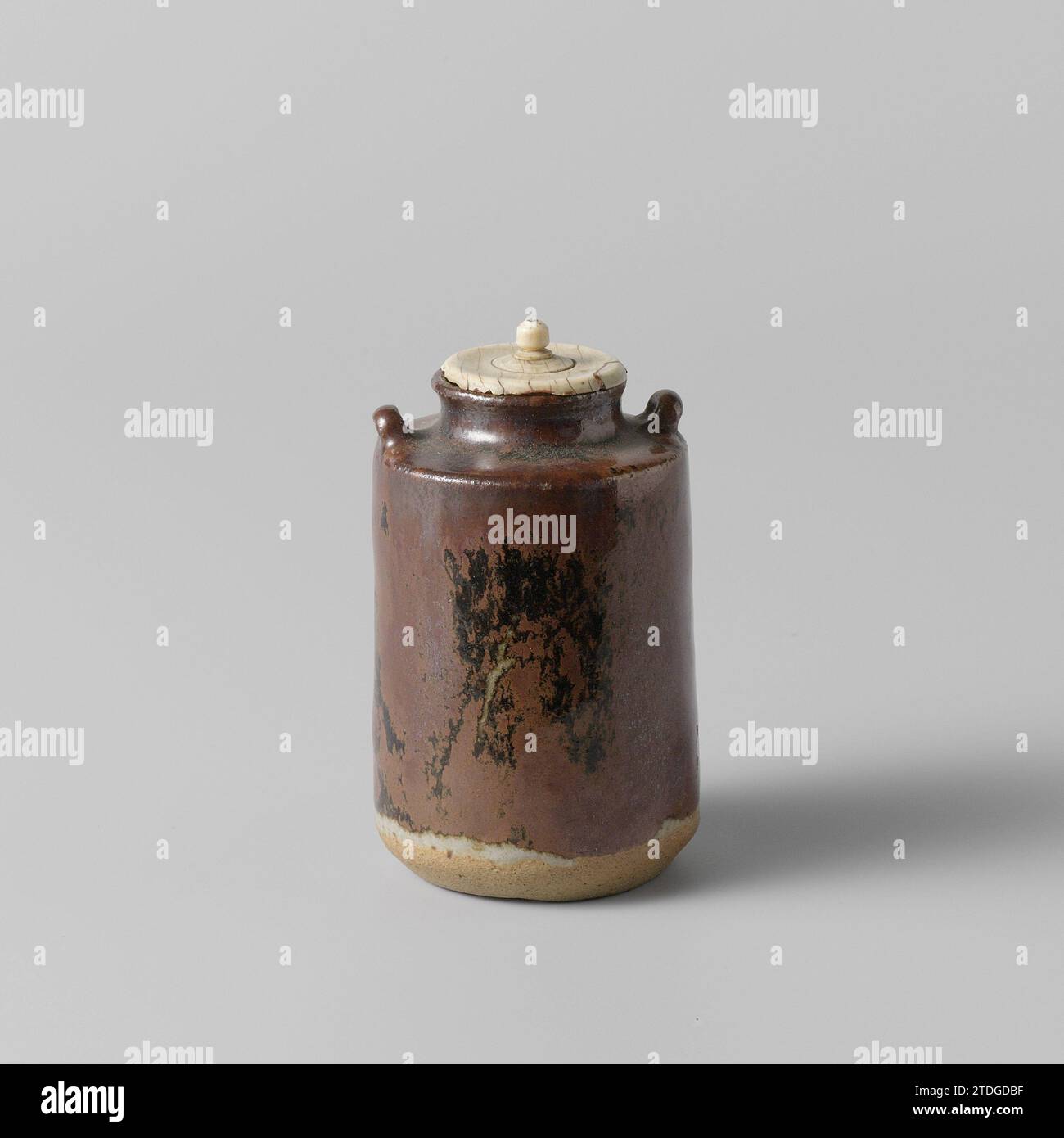 Caddy da tè con glassa marrone nera e due manici, anonimi, c. 1775 - c. 1824 parapolvere o sedia in gres con due orecchie sulla spalla e coperchio in avorio, parzialmente ricoperto da una glassa marrone con macchie nere. La parte inferiore del bus è non smaltita. SETO. Grès giapponese. glassa. Deksel: Parapolvere in vetrificazione avorio o sedia in gres con due orecchie sulla spalla e un coperchio in avorio, parzialmente ricoperto da uno smalto marrone con macchie nere. La parte inferiore del bus è non smaltita. SETO. Grès giapponese. glassa. deksel: vitrificazione avorio Foto Stock