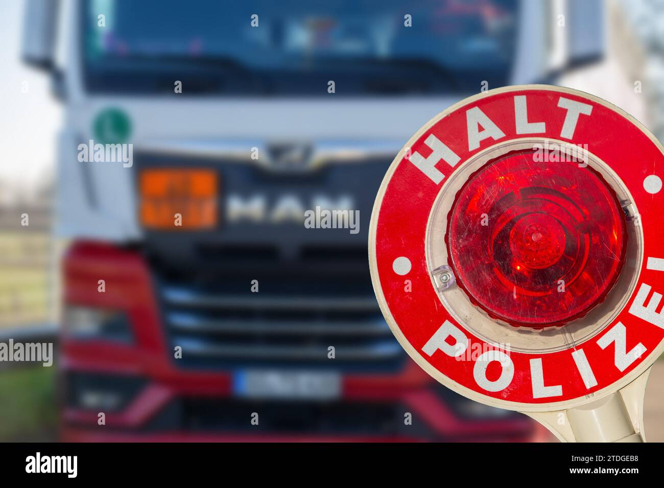Controllo di polizia (Germania): Primo piano di una cazzuola della polizia con l'iscrizione tedesca HALT POLIZEI (Stop Police) davanti a un camion (composizione) Foto Stock Controllo di polizia (Germania): Primo piano di una cazzuola della polizia con l'iscrizione tedesca HALT POLIZEI (Stop Police) davanti a un camion (composizione) Foto Stock
