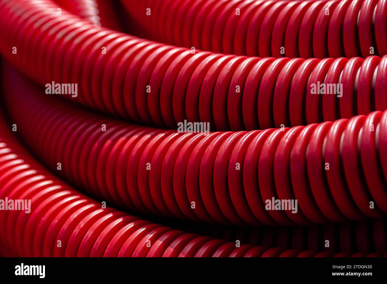 Diverse grandi bobine di tubi di plastica rossa utilizzate per la posa di tubazioni di irrigazione in giardini pubblici e parchi paesaggistici. Foto Stock