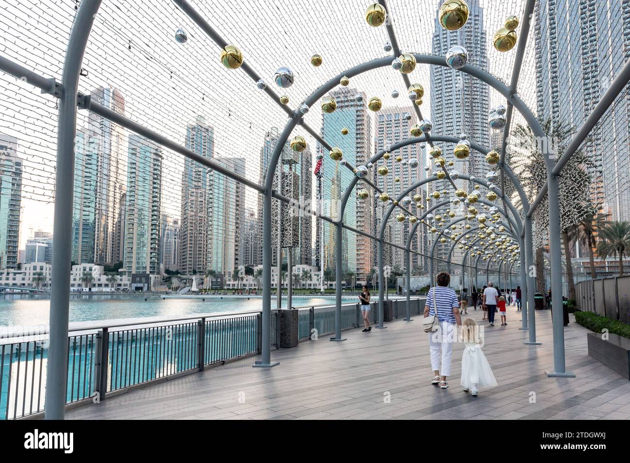 Dubai, Emirati Arabi Uniti. 18 dicembre 2023. I turisti camminano sull'aley tra le decorazioni natalizie di fronte all'architettura moderna, tra cui il Burj Khalifa nel centro di Dubai in un caldo giorno di dicembre. Credito: Dominika Zarzycka/Alamy Live News Foto Stock