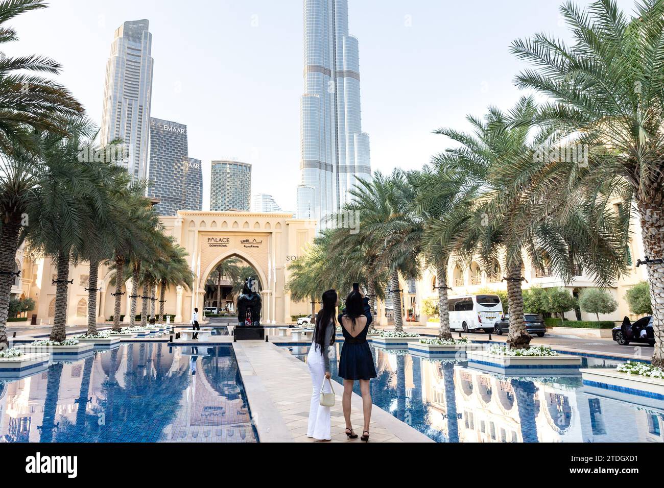 Dubai, Emirati Arabi Uniti. 18 dicembre 2023. Le donne camminano accanto a una piscina di fronte alla torre Burj Khalifa in un caldo giorno di dicembre nella città vecchia di Dubai. Credito: Dominika Zarzycka/Alamy Live News Foto Stock