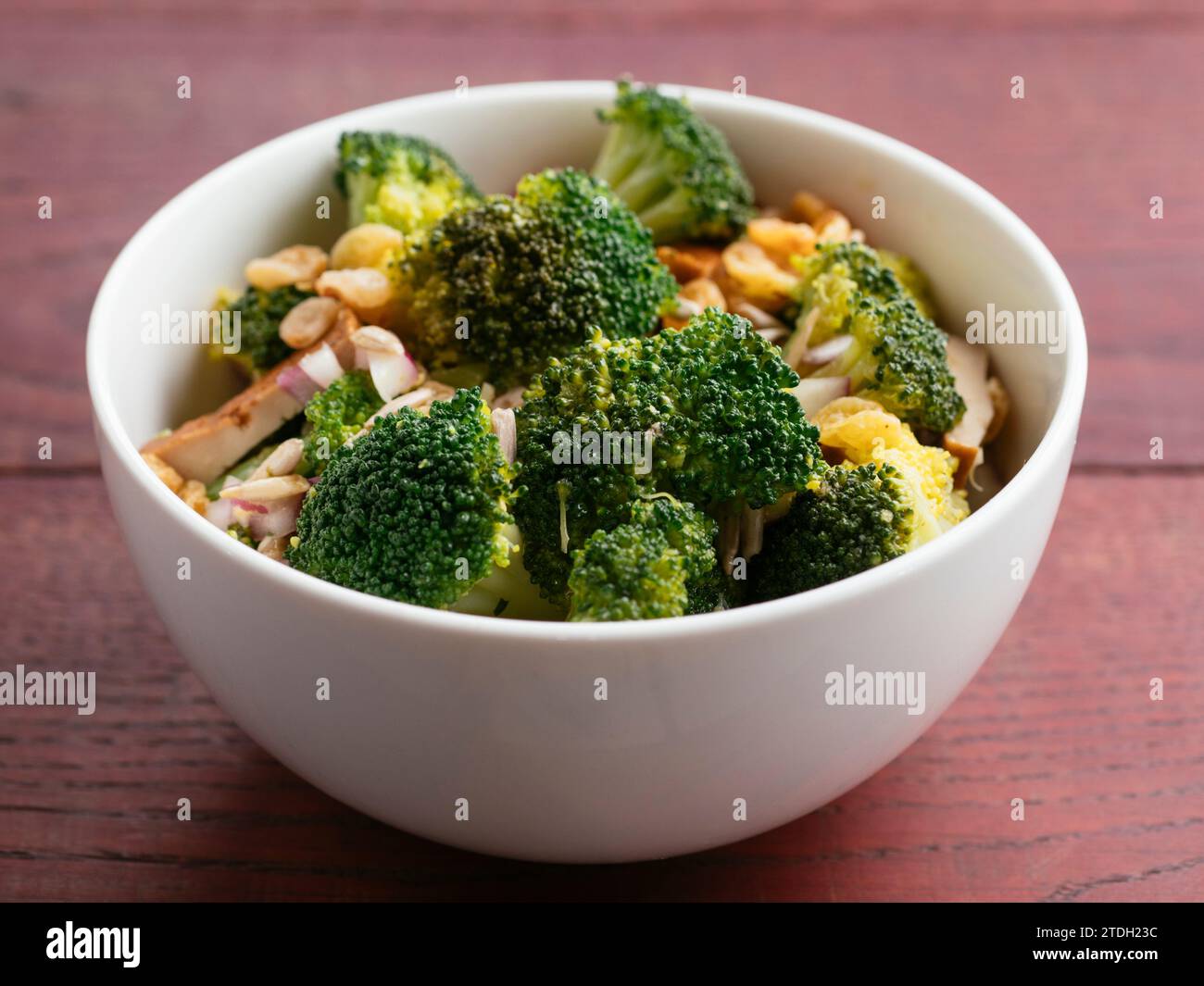 Insalata di broccoli vegani con broccoli, cipolla rossa, uvetta dorata, tofu affumicato e semi di girasole Foto Stock