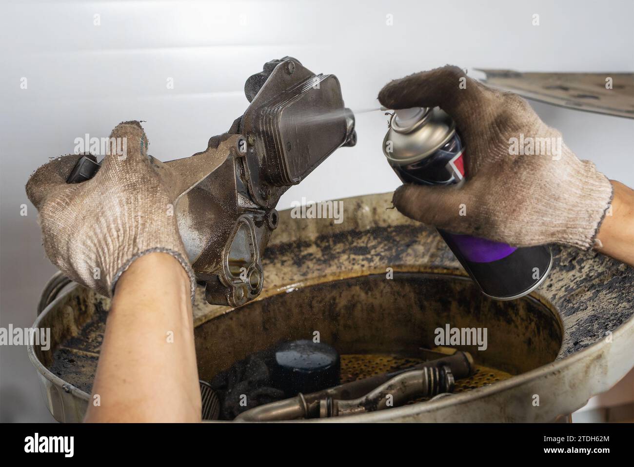 Un meccanico automatico pulisce lo scambiatore di calore di un'autovettura utilizzando uno spray detergente Foto Stock