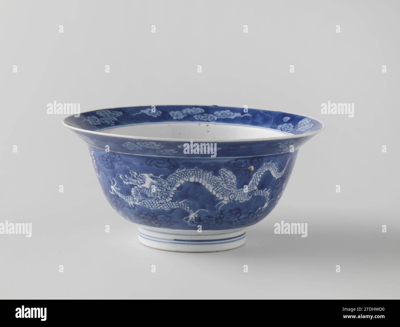 Ciotola con due perle che inseguono draghi tra le nuvole, anonima, c. 1680 - c. 1720 proviene da porcellana con un bordo spalmabile, dipinta in blu trasparente. La parete esterna è ricoperta di blu con una perla, quattro draghi nuvolosi tra le nuvole. Anche il bordo interno ed esterno sono rivestiti di blu con un motivo nuvola salvato. Sul fondo una roccia circondata da onde vorticose con la luna sopra di essa tra le nuvole. Contrassegnato sul lato inferiore con il marchio di sei personaggi di Keizer Chenghua in un doppio cerchio. Blue White. Porcellana cinese. glassa. La pittura/vitrificazione di cobalto (minerale) proviene da porcellana con spirito Foto Stock