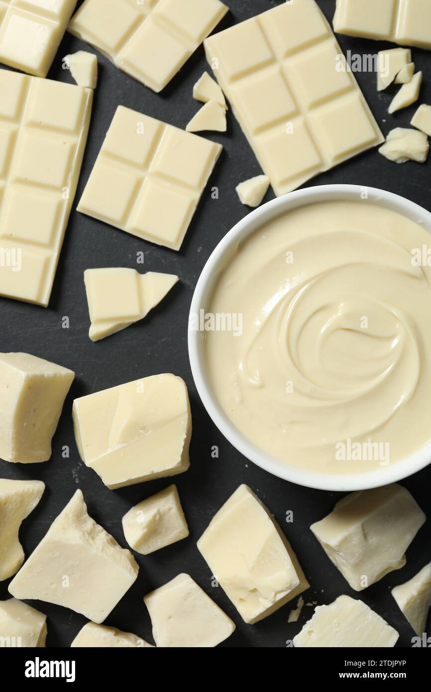 Gustosa pasta di cioccolato bianco in ciotola e pezzi su tavolo nero, piatto Foto Stock