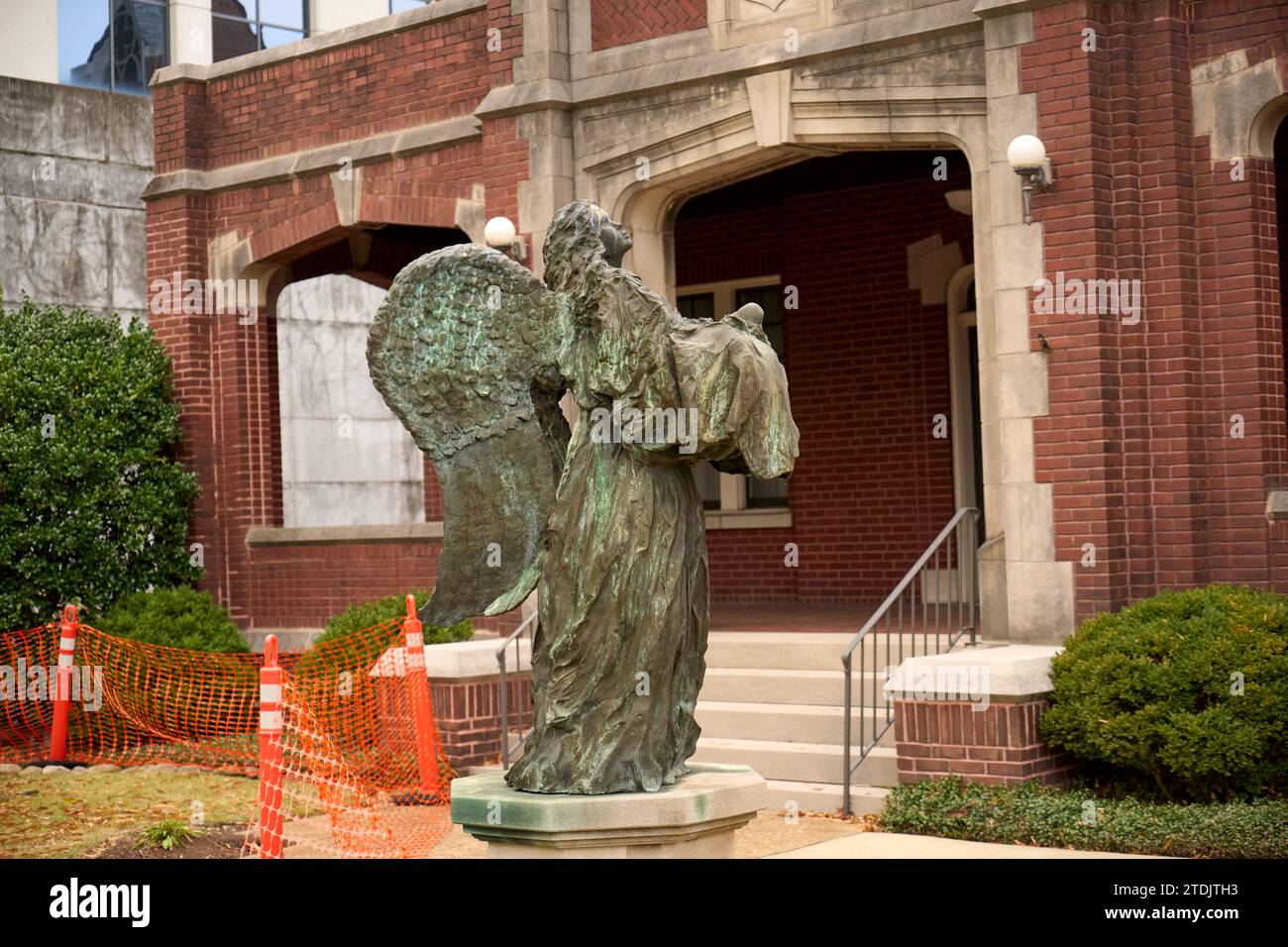 Urban Grace: Un angelo di bronzo sale davanti a un edificio in mattoni rossi, che abbellisce il rinnovamento della città. Foto Stock