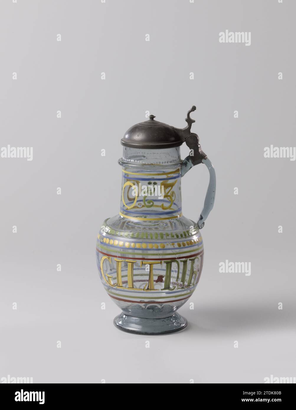 Brocca con coperchio e iscrizione: Bruder.es.gilt.dir.eins, Anonimo, 1603 terreno leggero inserito. Base liscia, leggermente conica con bordo smussato, corpo sferico sotto un collo quasi cilindrico. Auricolare a forma di C, liscio e acceso. Un filo di vetro liscio verniciato con punti verdi intorno al corpo all'altezza della parte inferiore dell'orecchio, un filo di vetro liscio sul collo all'altezza della parte superiore sulla parte superiore. Il corpo in bianco, giallo, blu, verde e rosso dipinto con l'iscrizione Bruder.es.gilt.dir.eins tra tubazioni lisce e imbevute. Sul collo a Geel l'anno 1603, le cifre separate dal flusso verde Foto Stock