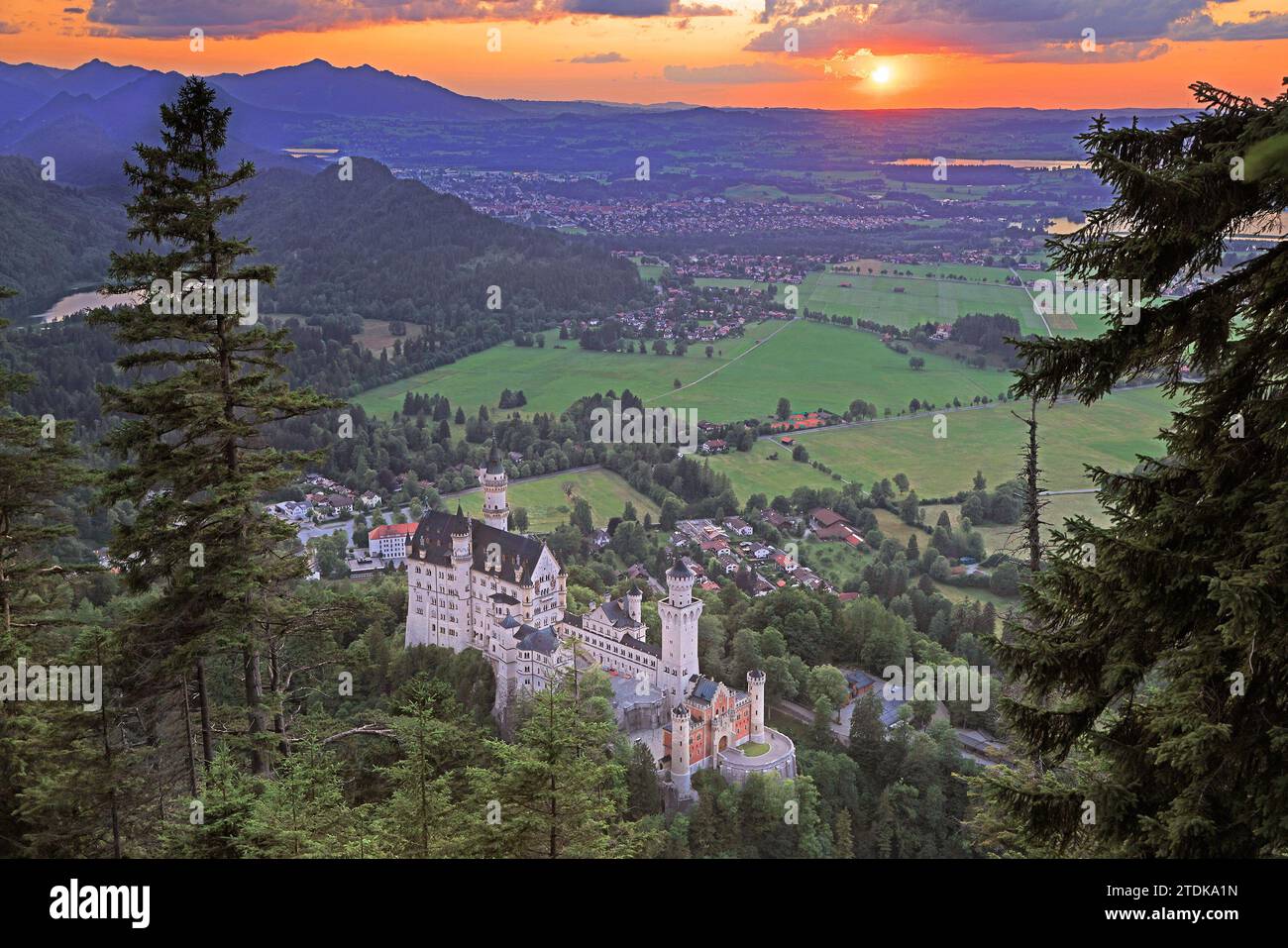 Vista aerea del castello di Neuschwanstein al tramonto con cielo arancione e sole sullo sfondo Foto Stock