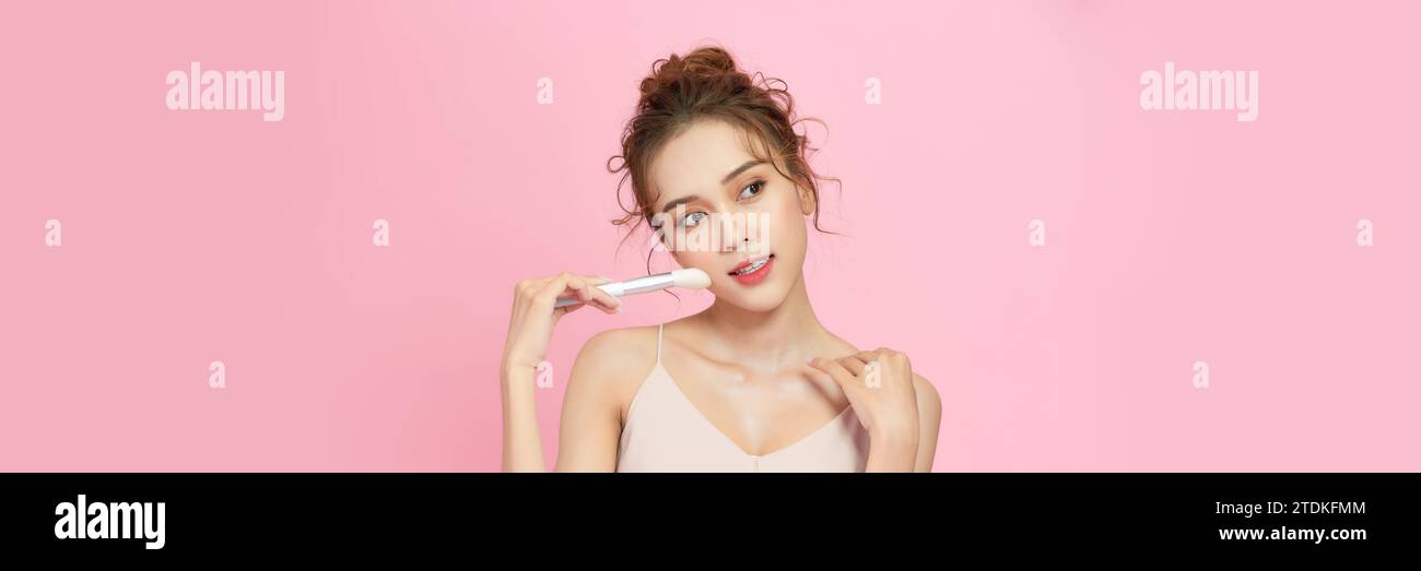 Bella giovane donna asiatica sorridere e tenere trucco pennello con pelle sana pulita e fresca Foto Stock