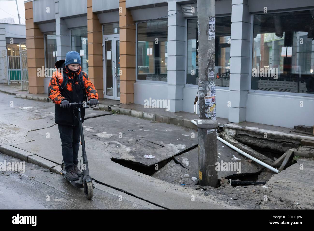 Kiev, Ucraina. 18 dicembre 2023. Un ragazzo cavalca uno scooter vicino a un mercato dove il suolo cade parzialmente in un tunnel della metropolitana a Kiev. Qualche giorno fa, la linea della metropolitana è stata chiusa per riparazioni a causa di un crollo del suolo e di una crepa nel tunnel. (Foto di Oleksii Chumachenko/SOPA Images/Sipa USA) credito: SIPA USA/Alamy Live News Foto Stock