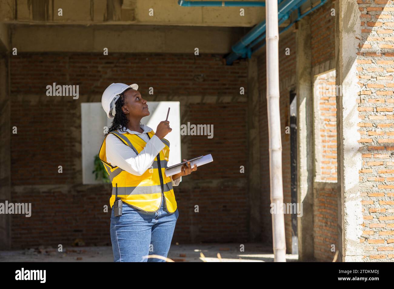 Donne ingegnere lavoratore professionista africano di colore che lavora ispezione controllo qualità del progetto di costruzione di case in cantiere. Foto Stock