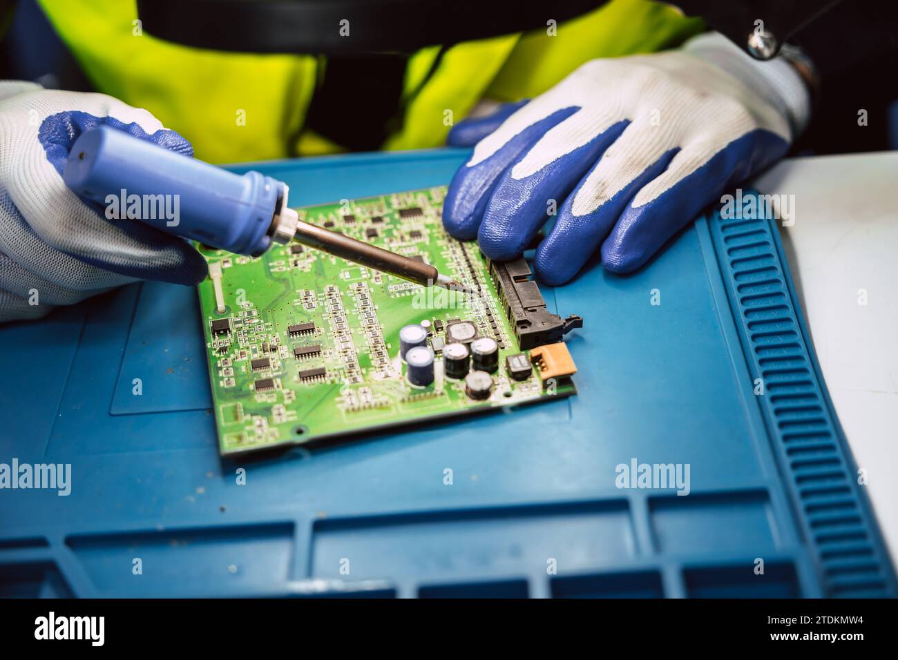 Tecnico elettricista che utilizza un saldatore a caldo per riparare riparazioni piccole riparazioni di circuiti stampati di computer digitali elettrici con stagno per saldatura e piombo Foto Stock