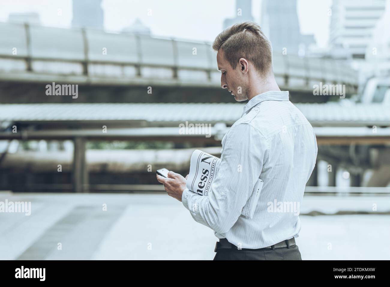 uomo d'affari con un giornale e uno smartphone per la lettura per gli uomini d'affari, aggiorna le informazioni di mercato, tutti i giorni, stile di vita urbano all'aperto. Foto Stock