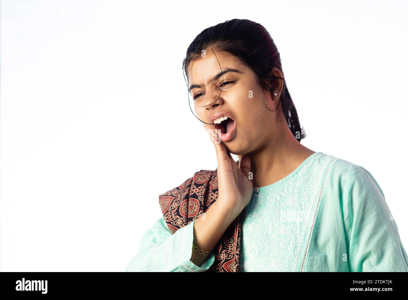 Una donna indiana che affronta problemi ai denti mostrando un'espressione dolorosa su sfondo bianco Foto Stock
