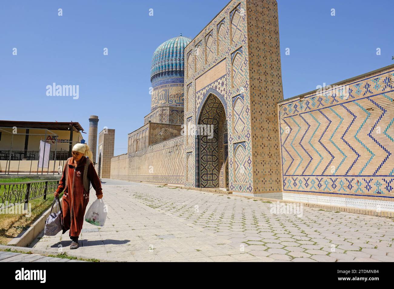 Samarcanda Uzbekistan una donna uzbeka locale cammina davanti alla moschea di Bibi Khanym Foto Stock