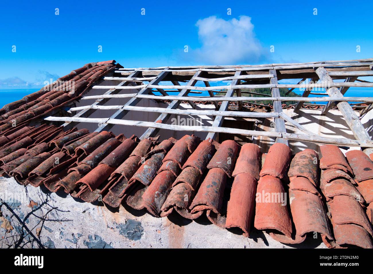 tetto semi demolito di una vecchia casa delle canarie. piastrelle rosse in un cielo blu. Foto Stock