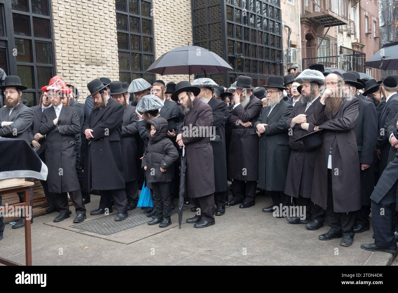 Una folla di ebrei chassidici in lutto ascolta gli elogi al funerale di un amato rabbino. A Brooklyn, New York Foto Stock