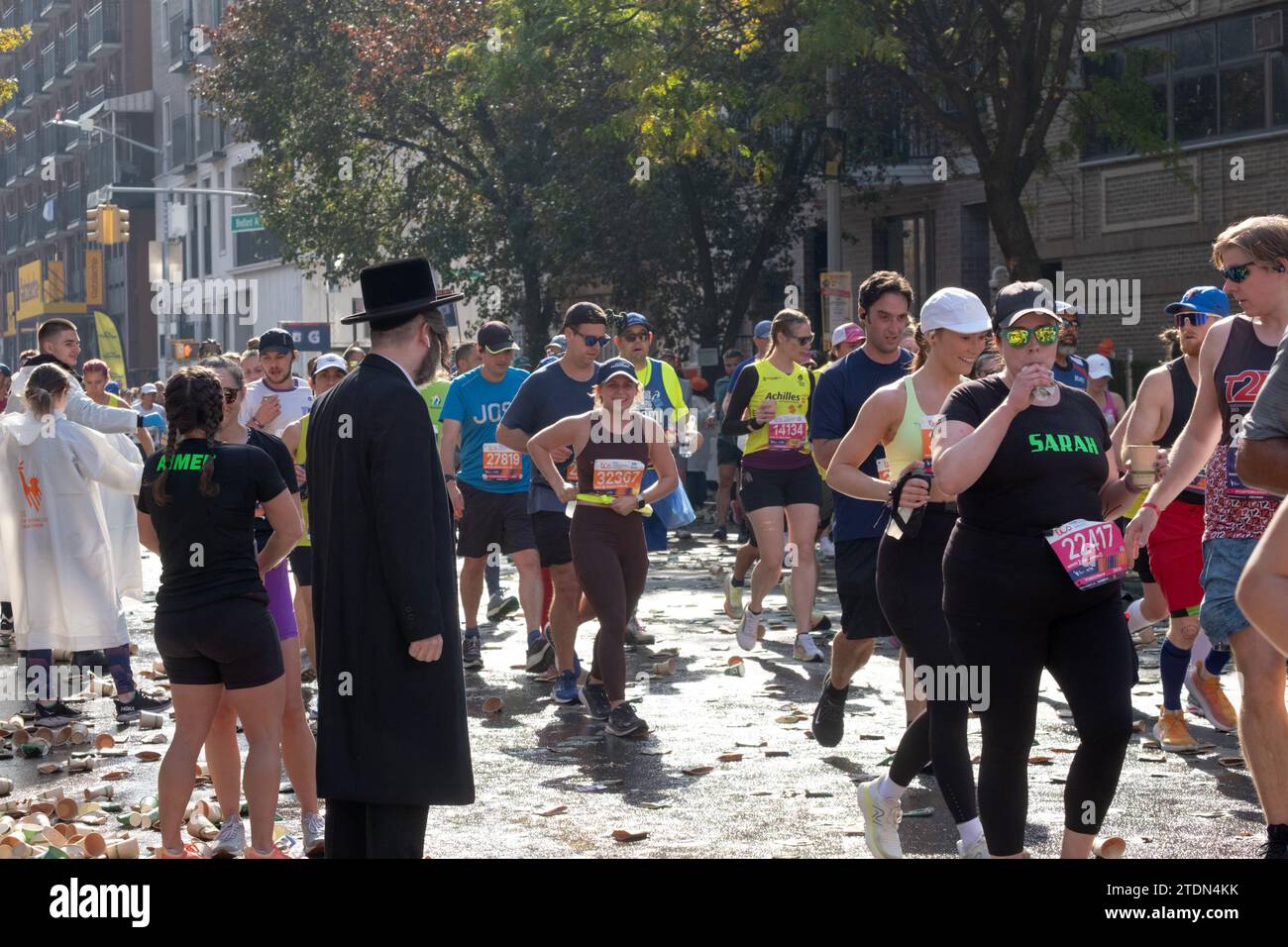 Alla 16 miglia della Maratona di New York, un ebreo ortodosso aspetta uno spazio tra i corridori per attraversare Bedford Ave. A Williamsburg, Brooklyn, New York. Foto Stock