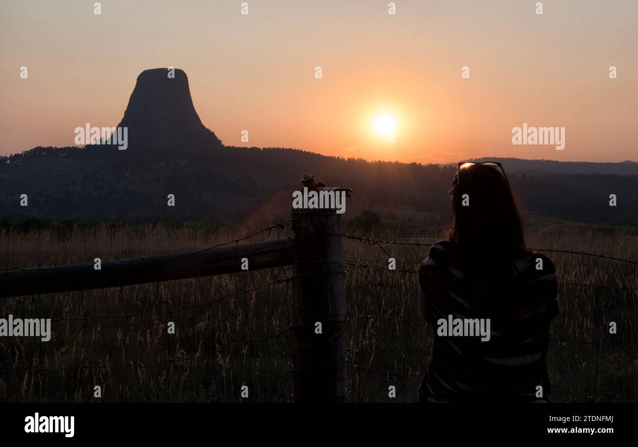 Silhouette di una giovane donna che guarda un tramonto autunnale dalla Devil Tower nel Wyoming. Foto Stock