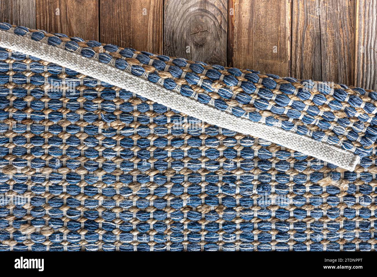 Tappeto in denim geometrico intrecciato a mano su pavimento in legno. Foto Stock