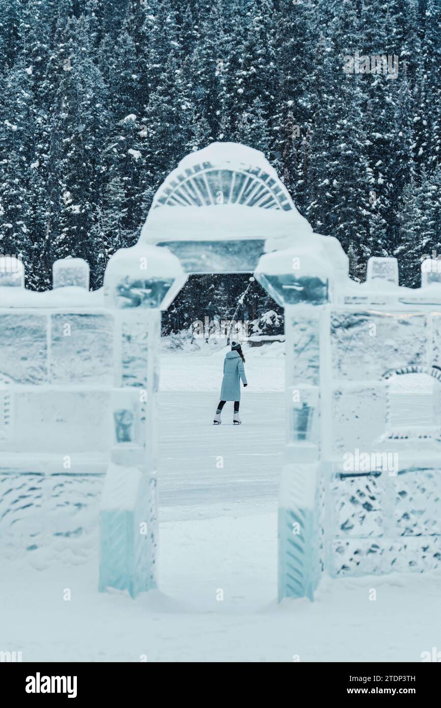Giovane turista con berretto in cappotto invernale che gioca a pattinare sul lago ghiacciato e a scolpire la parete di ghiaccio nel paese delle meraviglie invernali Foto Stock