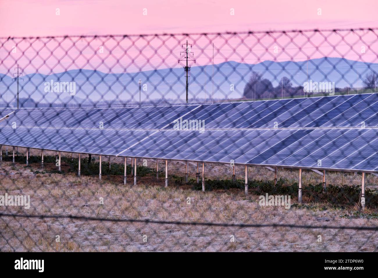 Parco della centrale di energia solare con pannelli oltre la recinzione a maglie di catena. Fonte di energia rinnovabile sovvenzionata sui terreni coltivabili. Europa. Repubblica Ceca. Inverno gelido Foto Stock