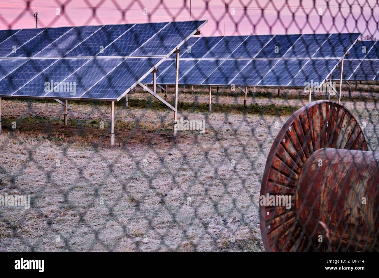 Parco della centrale di energia solare con pannelli oltre la recinzione a maglie di catena. Fonte di energia rinnovabile sovvenzionata sui terreni coltivabili. Europa. Repubblica Ceca. Inverno gelido Foto Stock