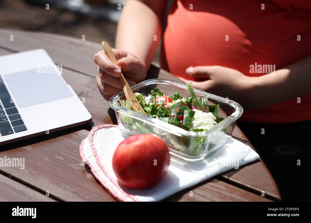 Una donna incinta sta facendo una pausa pranzo da sola al lavoro. Foto Stock