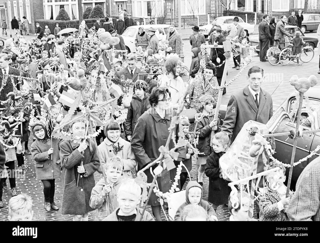 I bambini camminano in una parata la domenica delle Palme con il bastoncino pasquale decorato con rastrellatori, uova e arachidi sgusciate e sopra un gallo fatto di pane con rami di palma (bosso)., Haarlem, Zaanenstraat, Paesi Bassi, 03-04-1966, Whizgle News dal passato, su misura per il futuro. Esplora le narrazioni storiche, l'immagine dell'agenzia olandese olandese con una prospettiva moderna, colmando il divario tra gli eventi di ieri e quelli di domani. Un viaggio senza tempo che delinea le storie che plasmano il nostro futuro Foto Stock