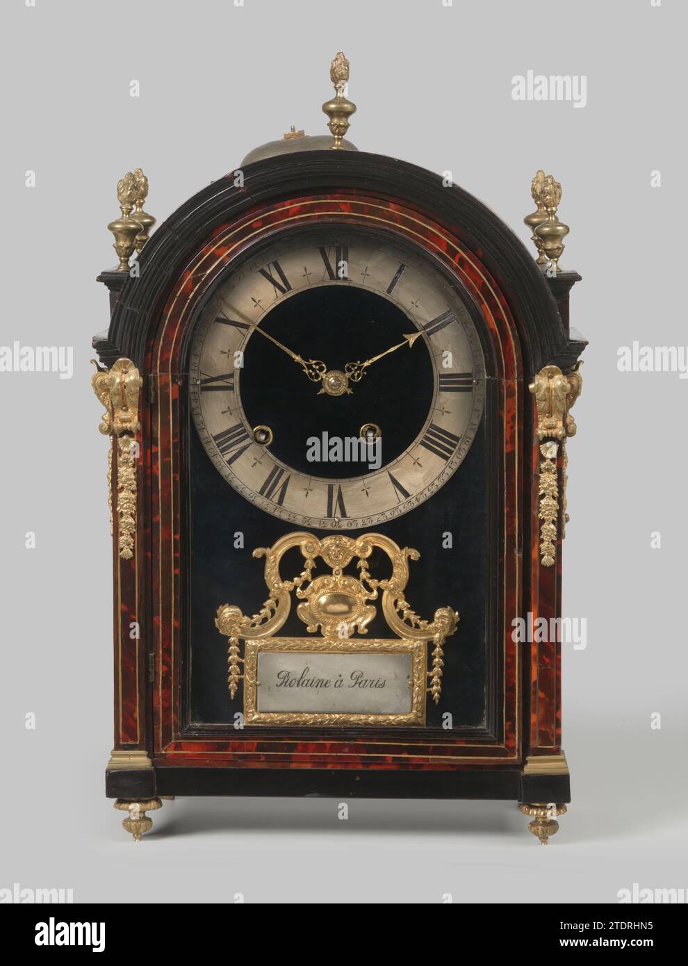 Orologio da tavolo, impiallacciato con tartaruga e legno di pera nero, con cornici in bronzo dorato. Coronato da cinque vasi con fiamme, Piolaine, 1700 - 1725 Orologio da tavolo, impiallacciato con tartaruga e legno di pera nera, con ferri da stiro in bronzo dorato. L'orologio, con gambe in ottone placcato oro, è chiuso nella parte anteriore da un tetto semicircolare, decorato agli angoli con pastella di bronzo dorato a forma di consolle e ghirlande. Cinque vasi in bronzo placcato oro con fiamme servono per una corona. La pastella sotto il quadrante mostra un cartiglio su una lista rettangolare, con l'iscrizione: Piolaine à Paris, fiancheggiata da una voluta A forma di S. Foto Stock