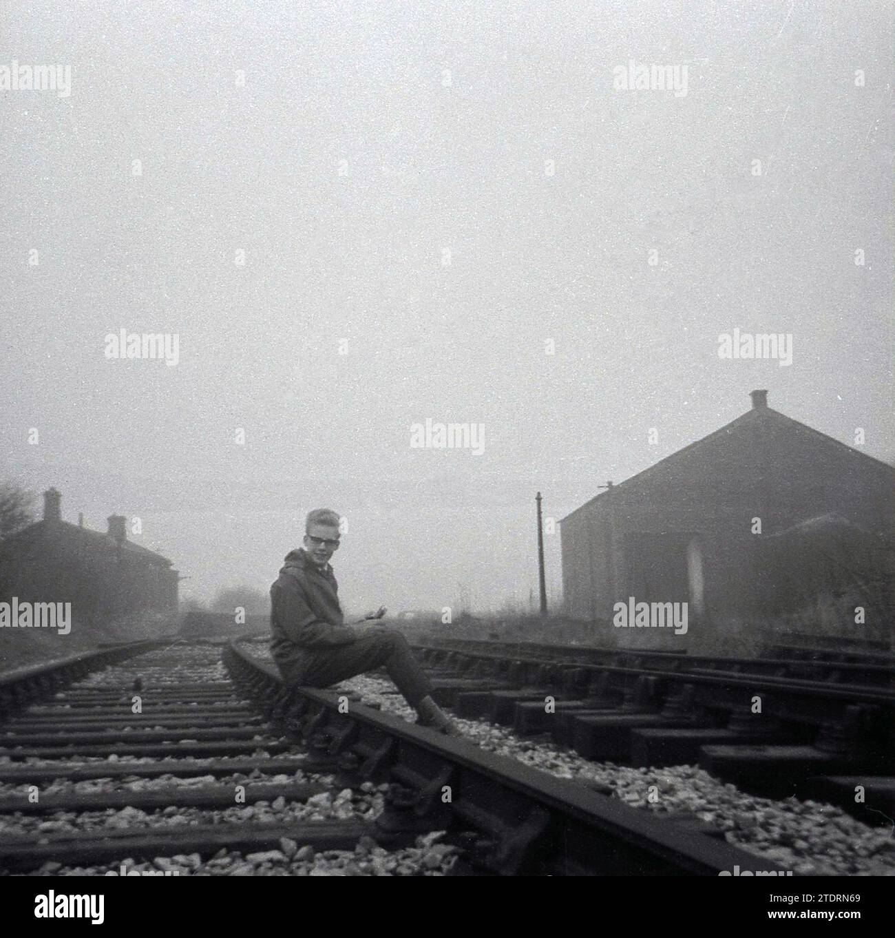 Anni '1960, storico, un adolescente seduto per una foto su una ferrovia, Inghilterra, Regno Unito. Foto Stock