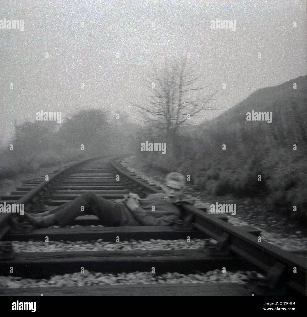 Anni '1960, storico, un ragazzo adolescente sdraiato su un binario ferroviario per una foto, Inghilterra, Regno Unito. Foto Stock