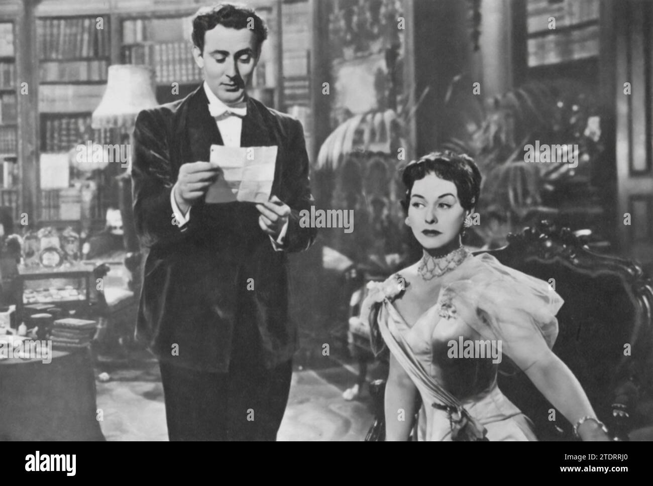 Michael Wilding e Paulette Goddard recitano in "An Ideal Husband" (1947), un adattamento cinematografico del dramma classico di Oscar Wilde. Wilding interpreta il suave ma tormentato Sir Robert Chiltern, il cui passato minaccia il suo presente, mentre Goddard interpreta l'astuta e affascinante signora Cheveley, che detiene un segreto che potrebbe rovinare la carriera di Chiltern. Le loro esibizioni, traboccanti di eleganza e spirito, danno vita alla versione satirica di Wilde sull'alta società vittoriana. Foto Stock