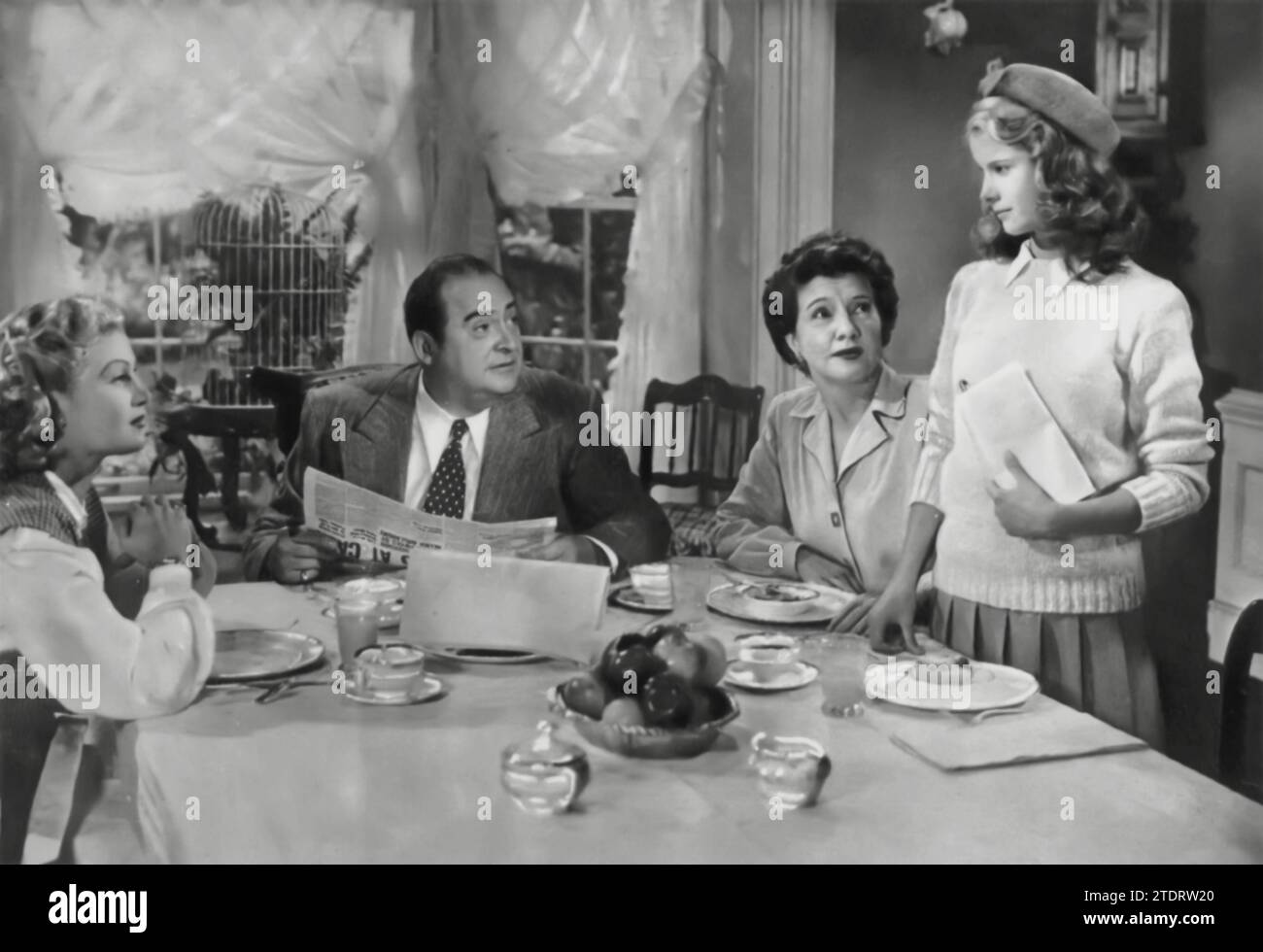 Joan Caulfield, Edward Arnold, Mary Philips e Mona Freeman appaiono nella commedia romantica Dear Ruth (1947). Il film ruota intorno a una ragazza adolescente, interpretata da Freeman, che scrive lettere a un soldato oltreoceano, fingendo di essere sua sorella maggiore, interpretata da Caulfield. I conseguenti equivoci e malintesi creano una storia divertente e commovente. Arnold e Philips aggiungono dinamicità alla famiglia, contribuendo al fascino del film. "Cara Ruth" è celebrata per la sua spensierata interpretazione dell'amore e per le complicazioni inaspettate che possono derivare da inganni innocenti. Foto Stock