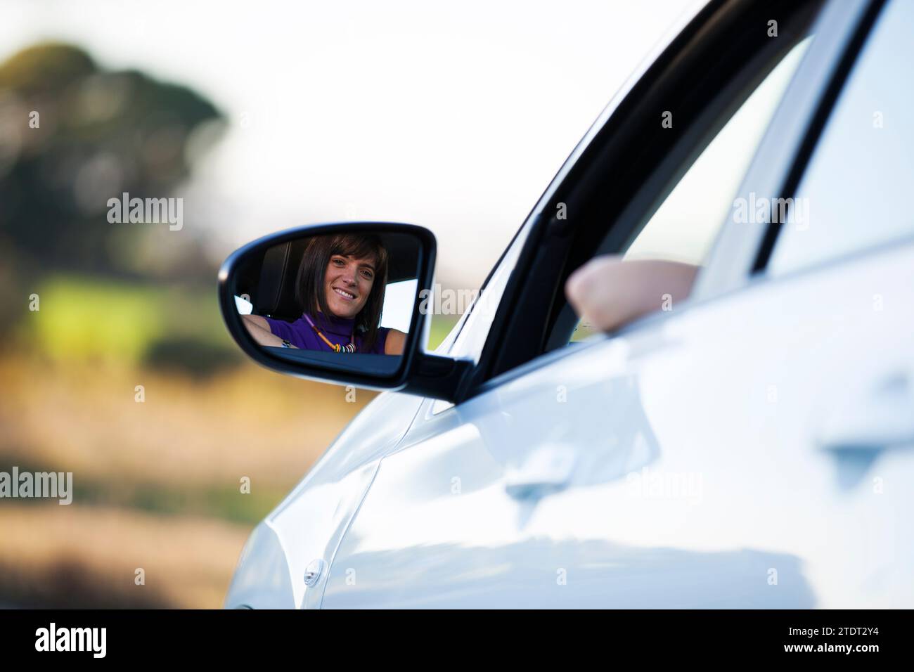 Bella donna volto riflesso sul lato specchio della sua nuova vettura Foto Stock