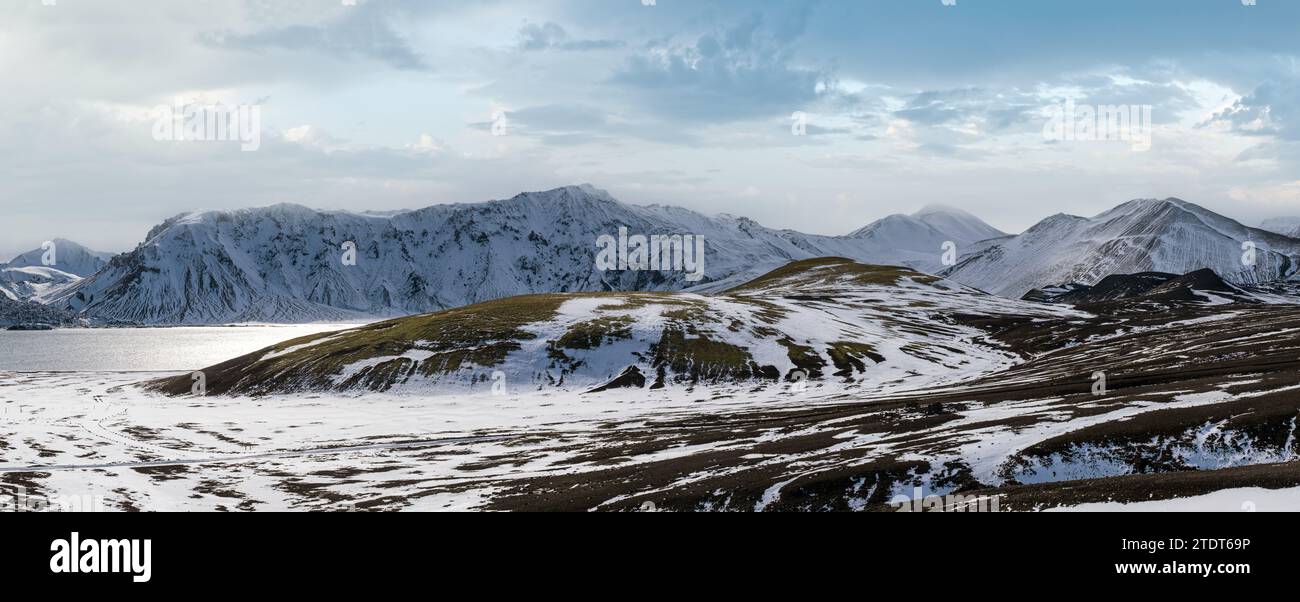 Cambiamenti di stagione negli altopiani islandesi. Montagne Landmannalaugar colorate sotto la copertura di neve in autunno. Lago Frostastadavatn ai piedi del moun Foto Stock