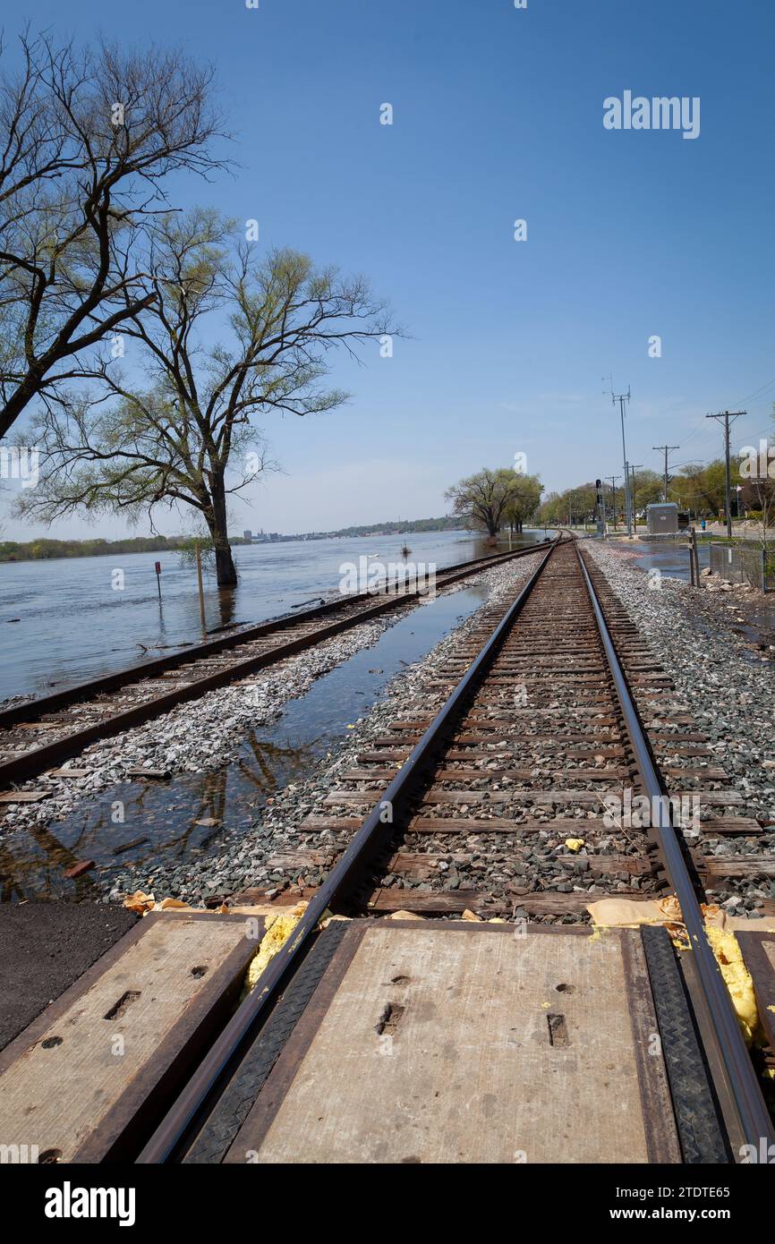 I binari ferroviari stanno per essere superati da un fiume allagato. Foto Stock