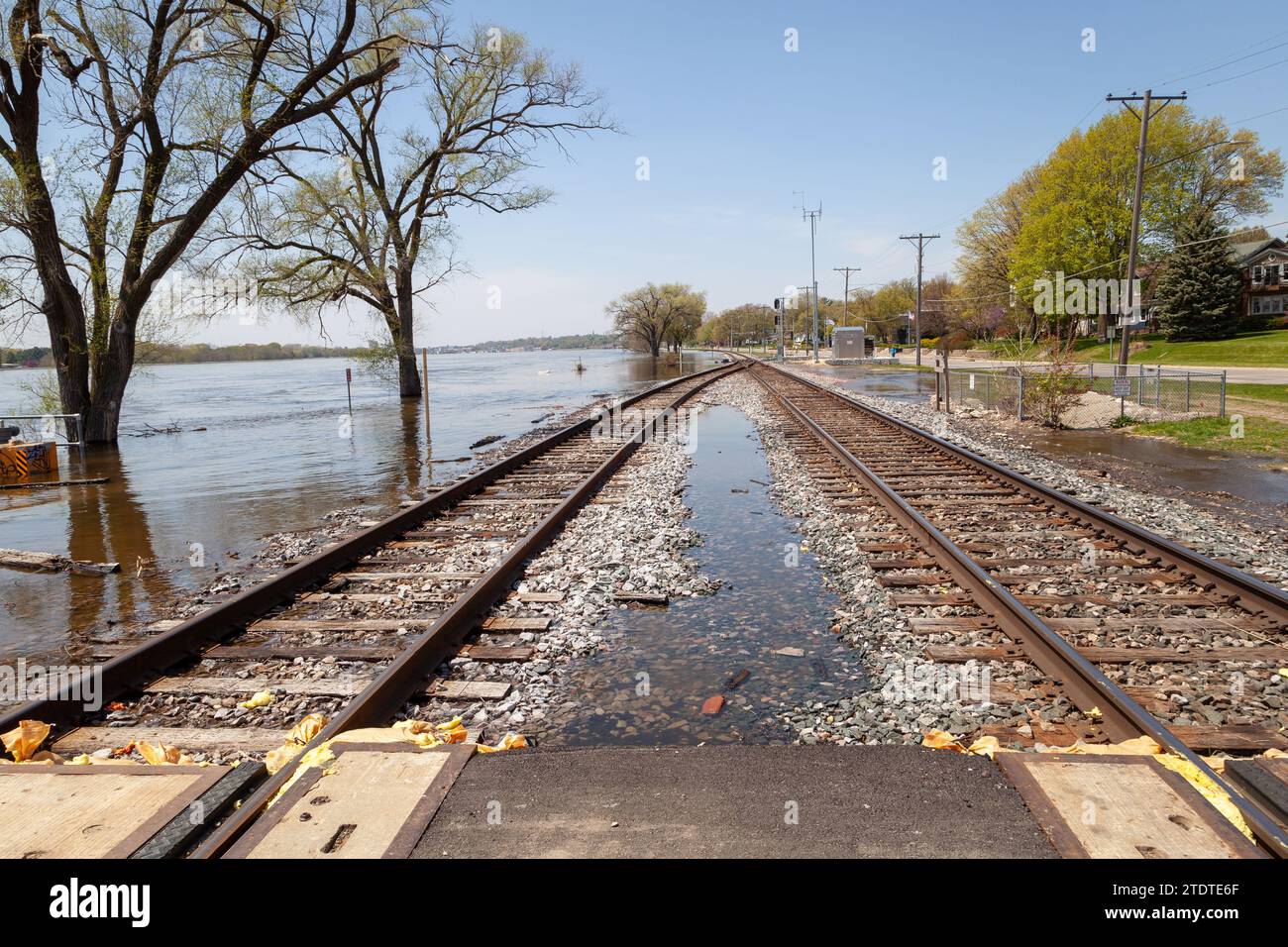 I binari ferroviari stanno per essere superati da un fiume allagato. Foto Stock