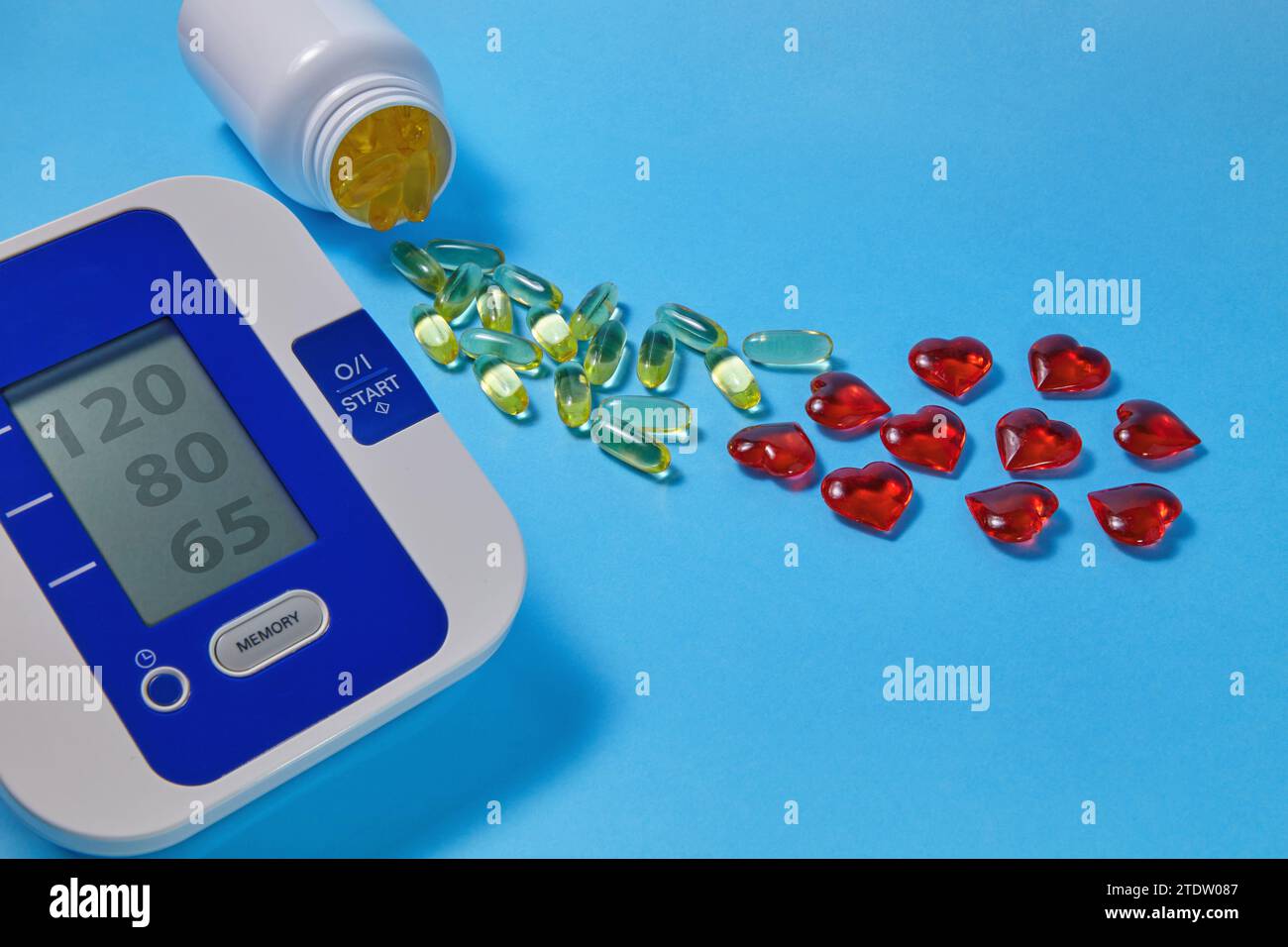 Acidi grassi polinsaturi Omega-3 e tonometro cardiaco decorativo rosso su sfondo blu. Prevenzione e trattamento dell'aterosclerosi Foto Stock