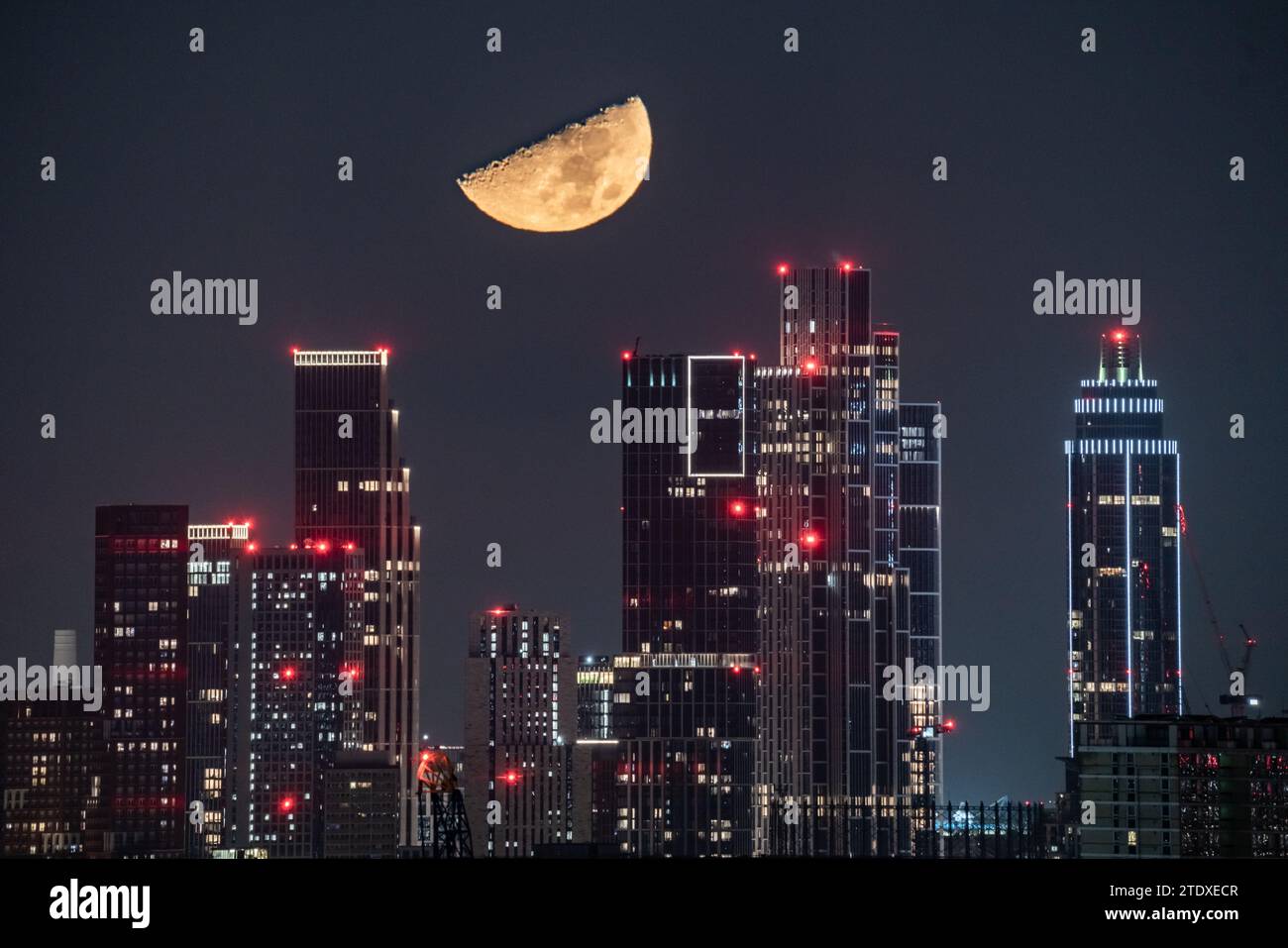 Londra, Regno Unito. 19 dicembre 2023. Tempo nel Regno Unito: Il primo quarto di luna al 49,8% si erge su edifici cittadini, tra cui la One St George Wharf Tower, che si muove in direzione ovest alle 23:55 di martedì sera. Crediti: Guy Corbishley/Alamy Live News Foto Stock
