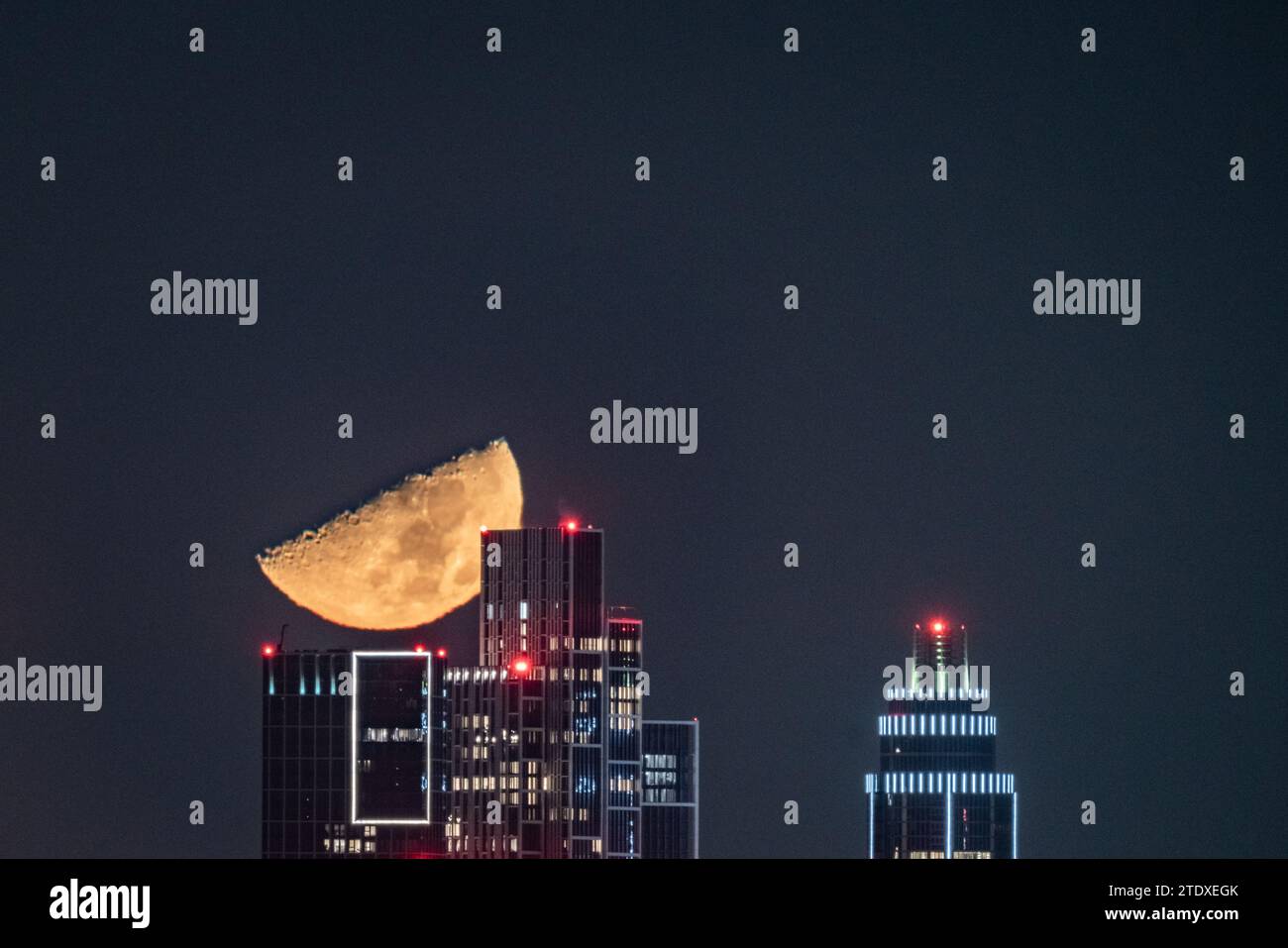 Londra, Regno Unito. 19 dicembre 2023. Tempo nel Regno Unito: Il primo quarto di luna al 49,8% si erge su edifici cittadini, tra cui la One St George Wharf Tower, che si muove in direzione ovest alle 23:55 di martedì sera. Crediti: Guy Corbishley/Alamy Live News Foto Stock